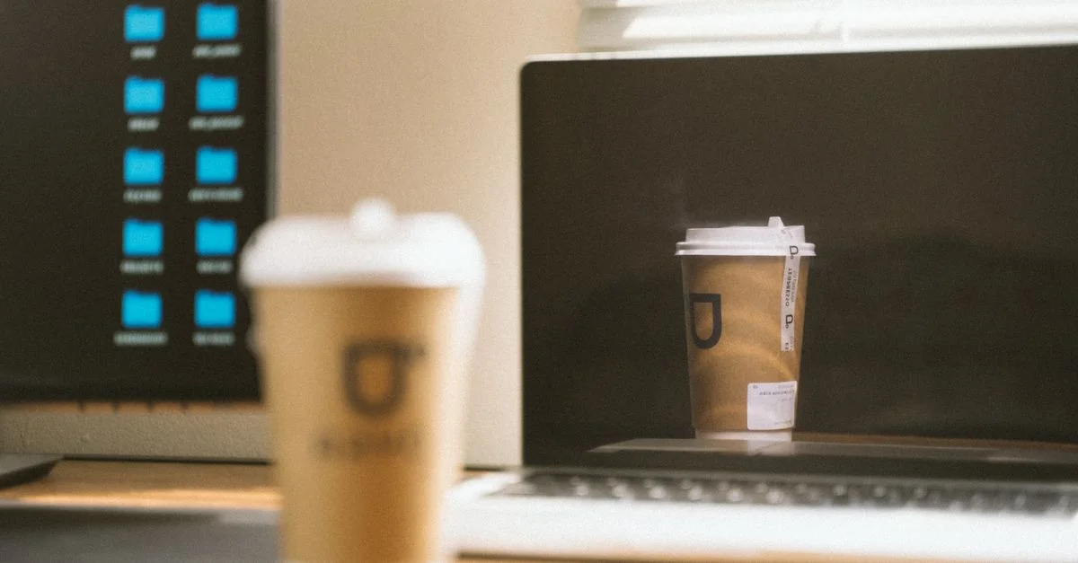 Un bureau moderne avec un ordinateur portable et une tasse de café, reflétant un environnement de travail décontracté.