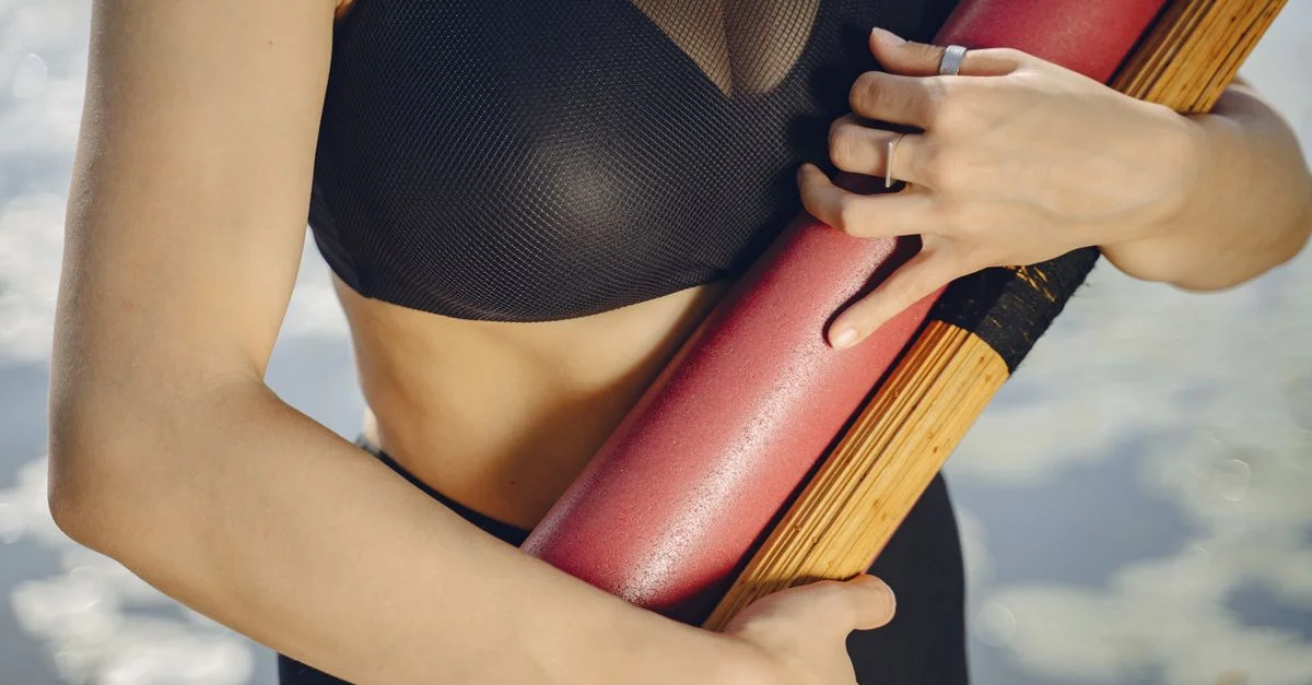Gros plan sur une femme en vêtements de sport tenant un tapis de yoga en plein air, prête pour une séance d'entraînement.