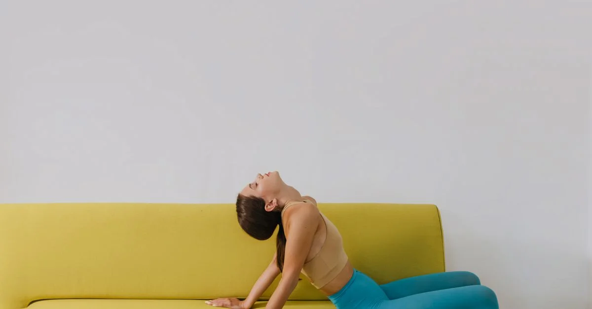 Femme élégante en collants turquoise s'appuyant sur un canapé moderne jaune.